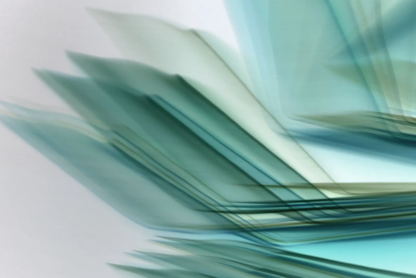 Aufgefächerte Glasscheiben in Blaugrün vor hellem Hintergrund